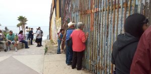 Men and women talking, eating, and looking through U.S. and Mexico Border